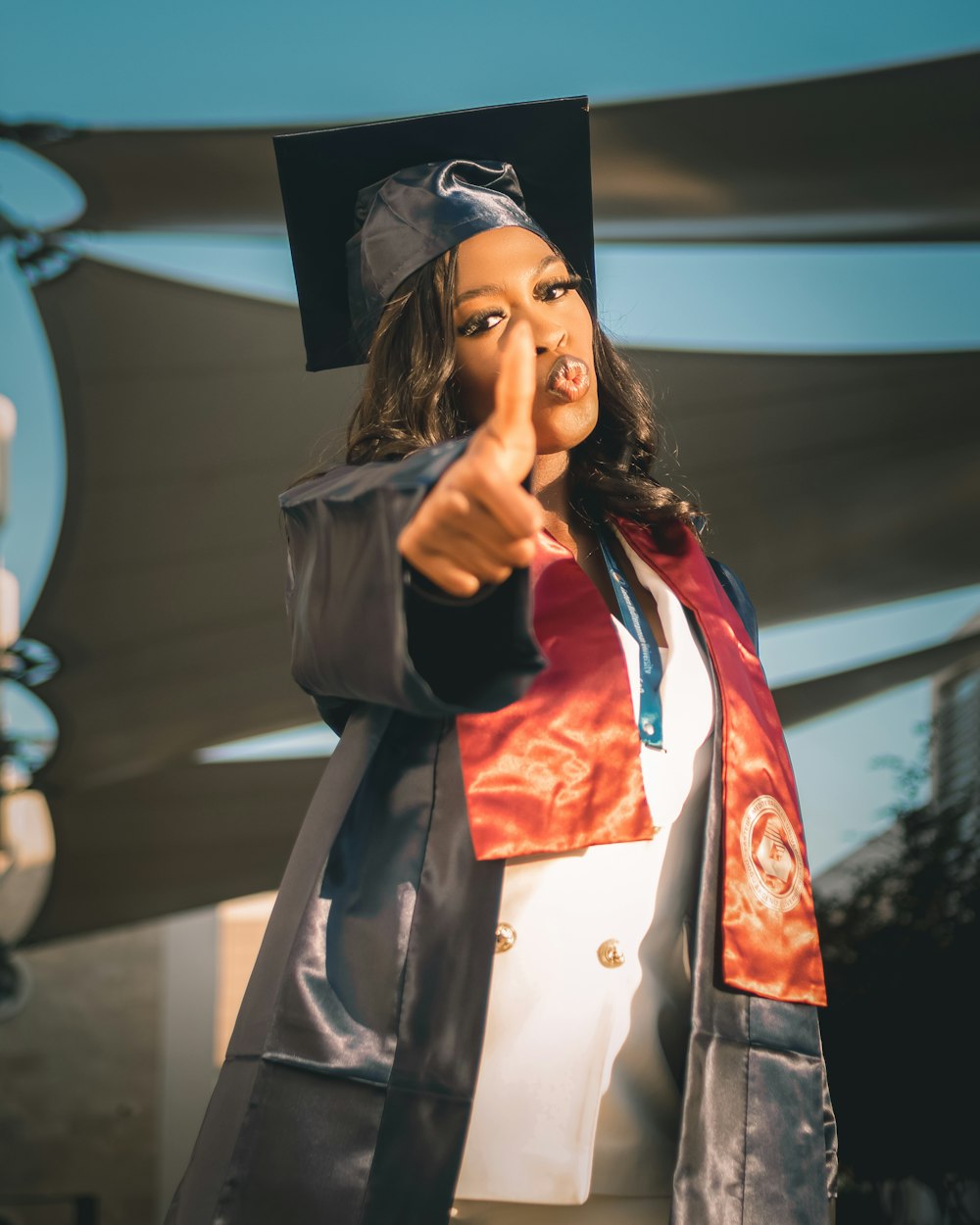 a woman in a graduation gown pointing at the camera