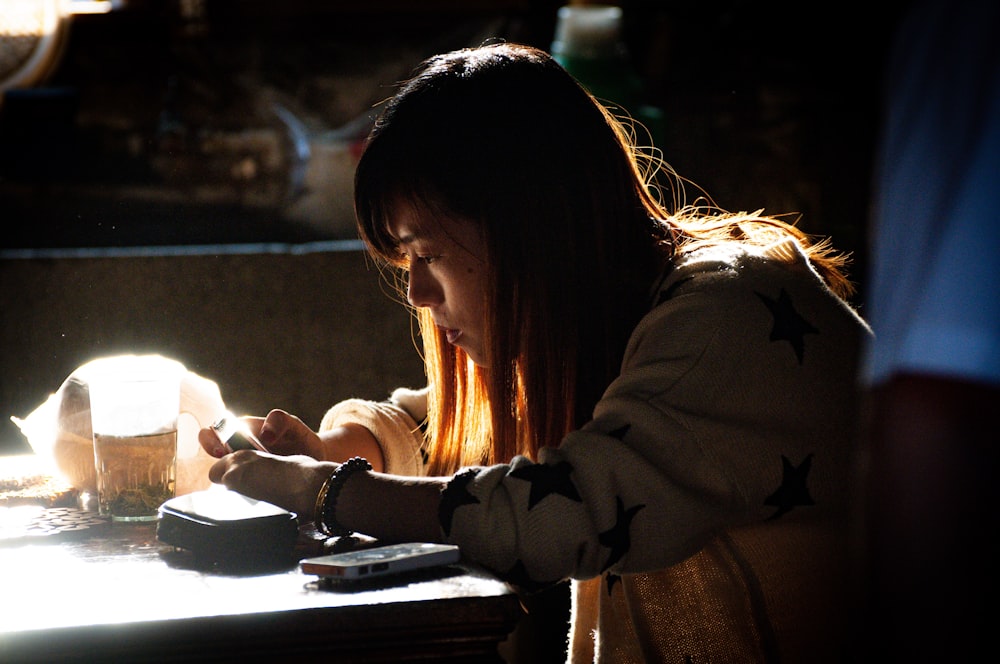 a woman sitting at a table using a cell phone