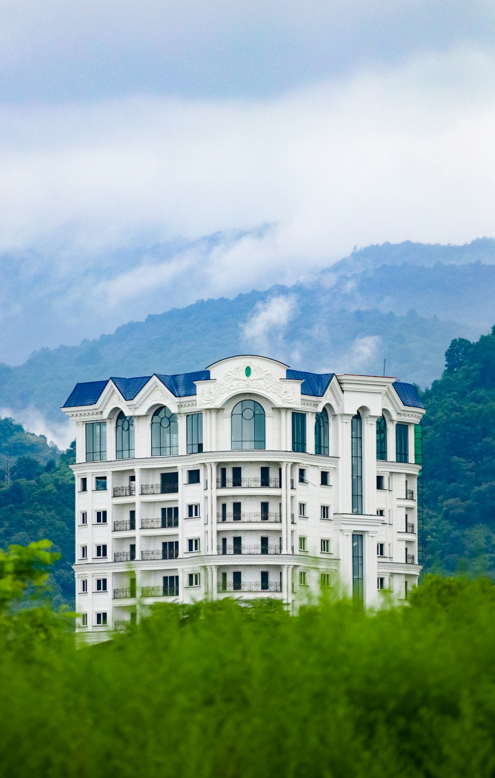 a tall white building sitting on top of a lush green hillside
