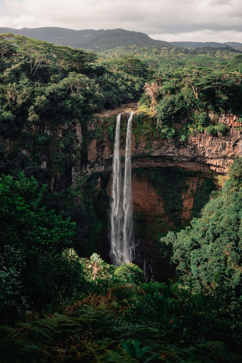 a large waterfall in the middle of a lush green forest
