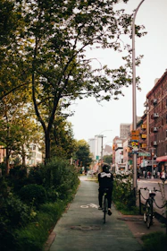Cycling influencer riding through a leafy city park with camera gear attached.