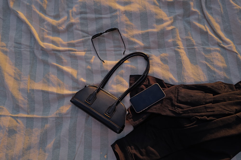 a pair of glasses and a bag laying on a bed