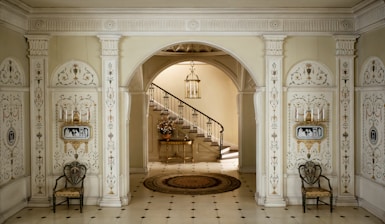 a hallway with a staircase and two chairs