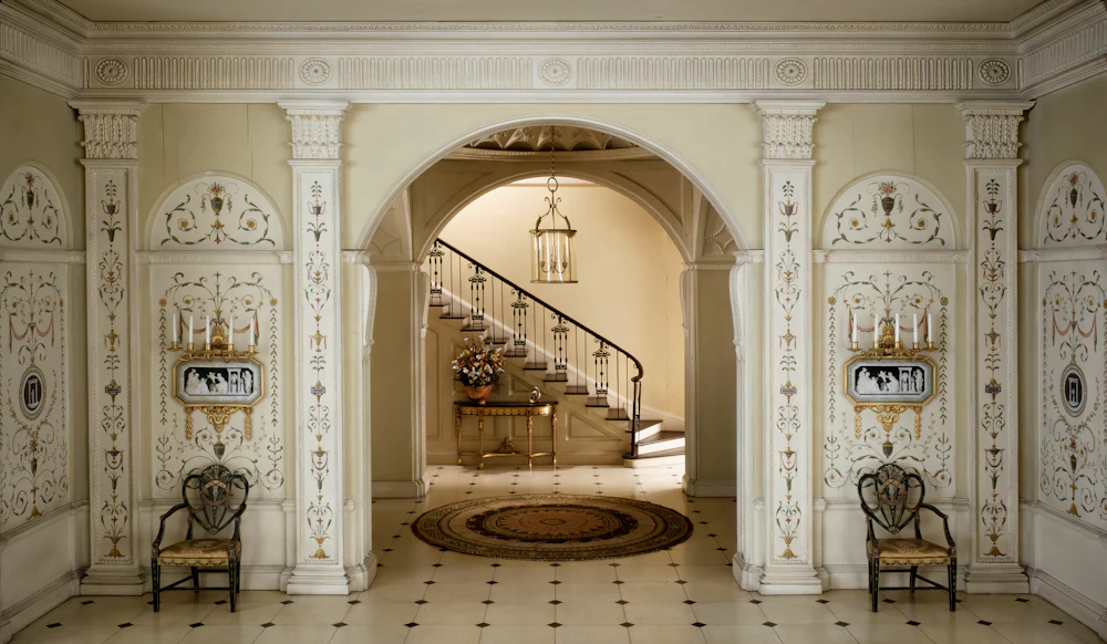 Period entrance hall with a stone archway framing a curved staircase