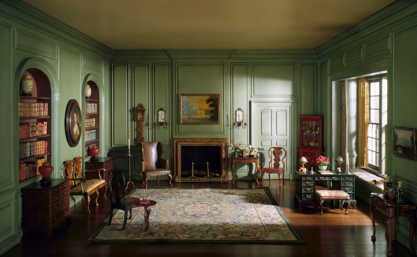 Period room with green walls, a fireplace and a patterned rug