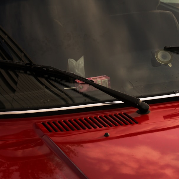 a close up of a red car with a cat in the window