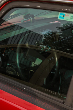 A close-up of a learner gripping the steering wheel inside a car with Luton landmarks visible through the window.