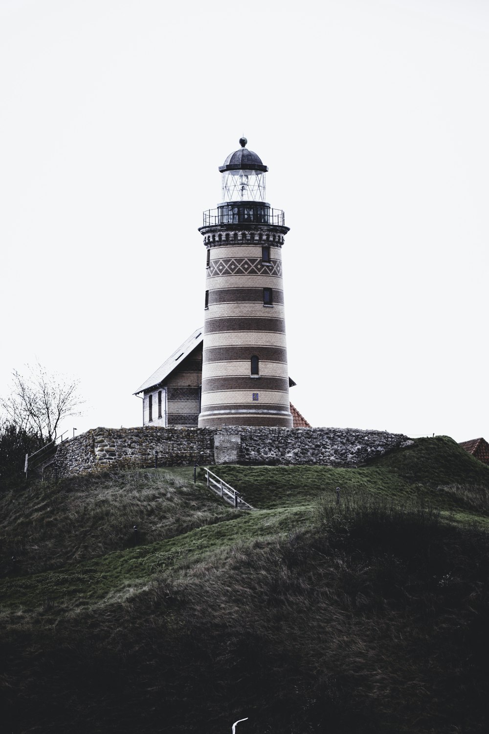 a lighthouse on top of a hill on a cloudy day
