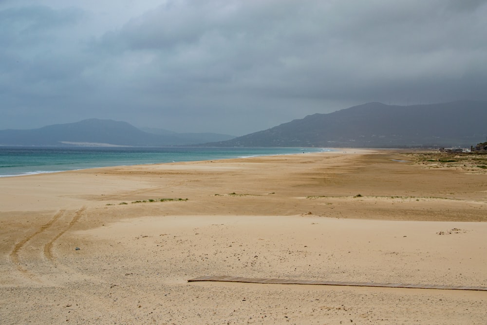 Una playa de arena con montañas en la distancia