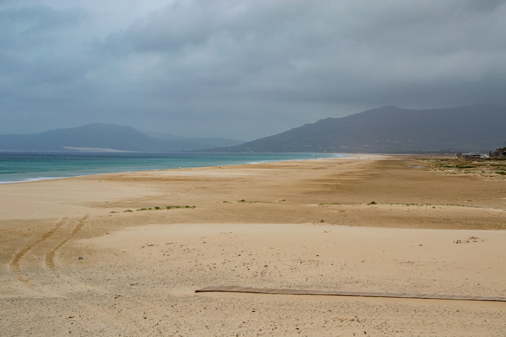 a sandy beach with mountains in the distance