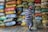 Close-up of a smiling Indian man holding a sack of premium rice in a vibrant warehouse.