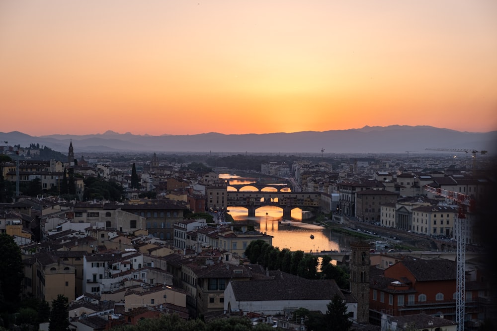 the sun is setting over a city with bridges