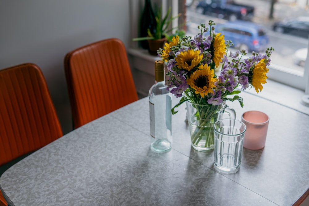 a table with two vases of sunflowers and a candle on it