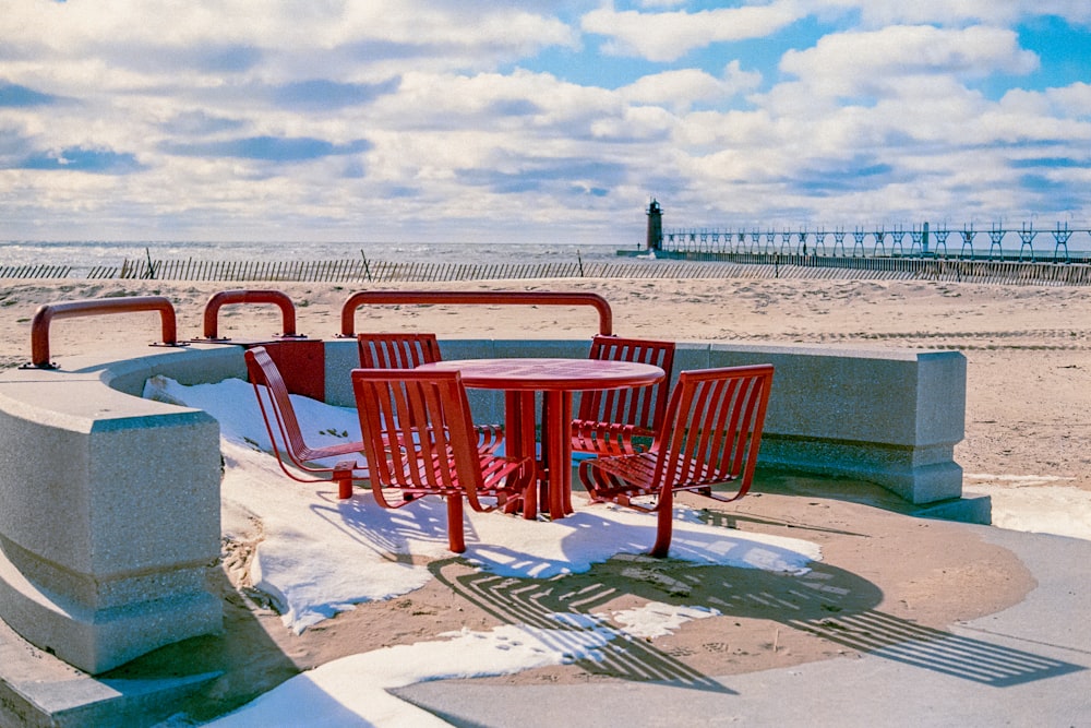 a red table and chairs sitting on a sandy beach