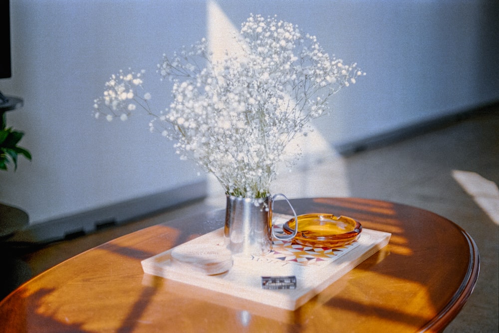 a wooden table topped with a vase filled with white flowers