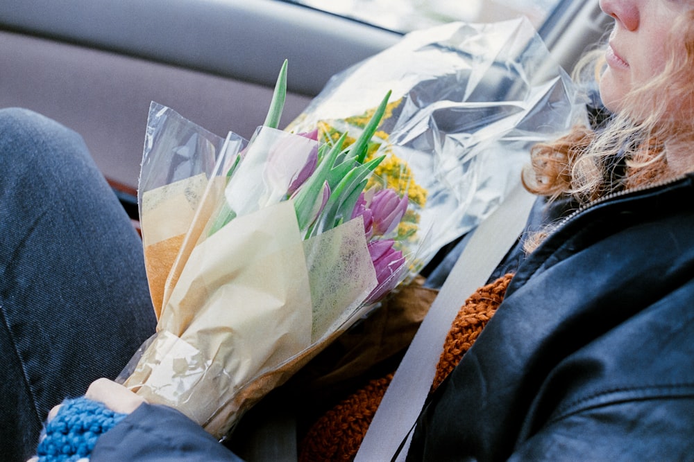a woman sitting in a car holding a bouquet of flowers