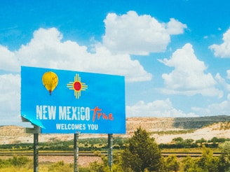 a blue sign that says new mexico plaza welcomes you