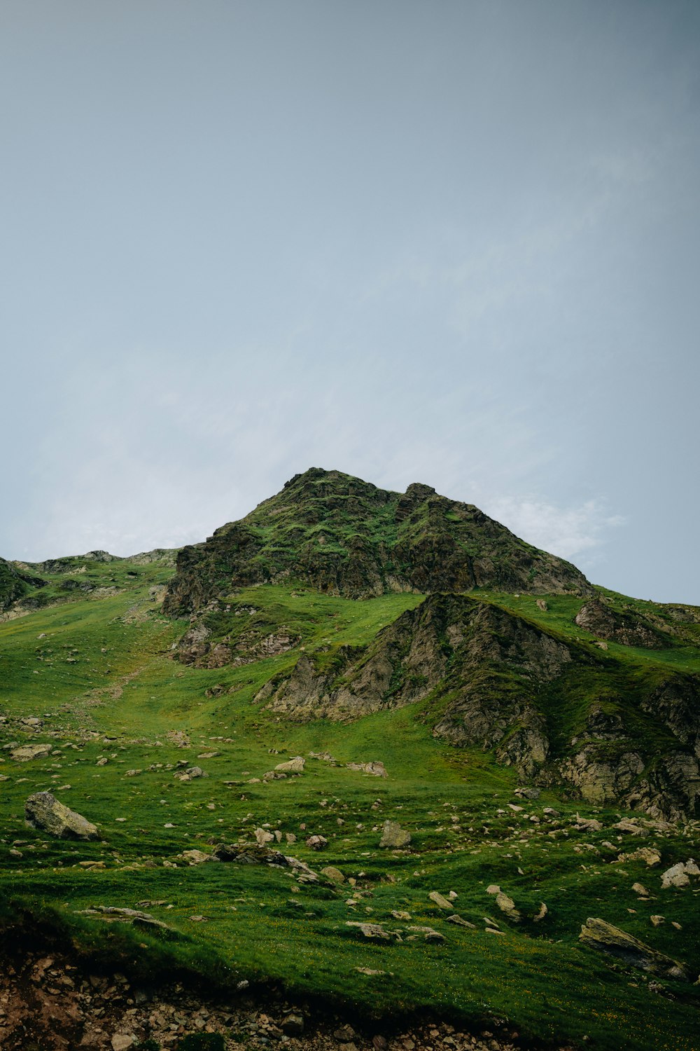 a grassy hill with a small hill in the background