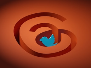 An orange background featuring a stylized symbol resembling an '@' sign with the blue outline of a Twitter bird logo in the center.
