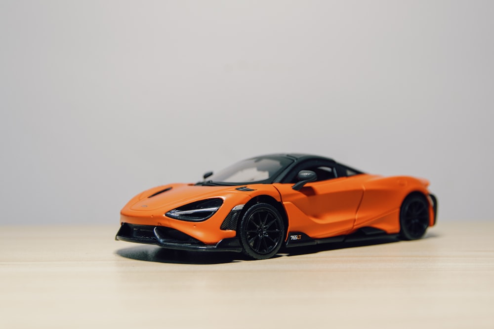 an orange sports car sitting on top of a wooden table