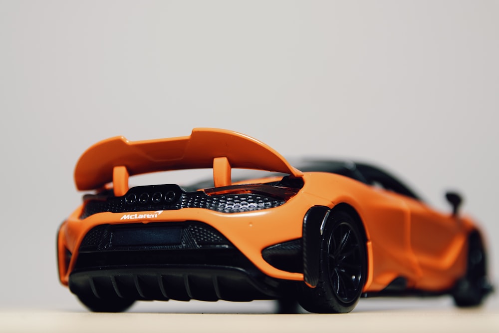 an orange toy car on a white surface