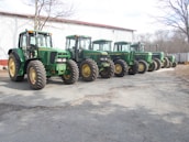 Row of modern farm equipment arranged neatly on a farm, ready for use.