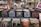 A collection of vinyl records is displayed in black crates on shelves. The surroundings include various music paraphernalia such as CDs, posters, and decorative items. There are also some framed artworks and magazine covers on display, contributing to a vintage and eclectic atmosphere.