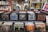 A collection of vinyl records is displayed in black crates on shelves. The surroundings include various music paraphernalia such as CDs, posters, and decorative items. There are also some framed artworks and magazine covers on display, contributing to a vintage and eclectic atmosphere.