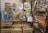 A collection of vintage comic books and magazines is displayed on metal racks. Titles like Oswald, Spider-Man, Hulk, and Jack and Jill are visible. The comics are enclosed in plastic sleeves, and some racks are labeled with categories like Marvel Comics, Charlton Comics, Disney & Dell, and Archie Comics. A sign indicates that the comics/mags are priced at $3 unless marked otherwise. There are various colors and illustrations on the covers, showcasing different characters and themes.