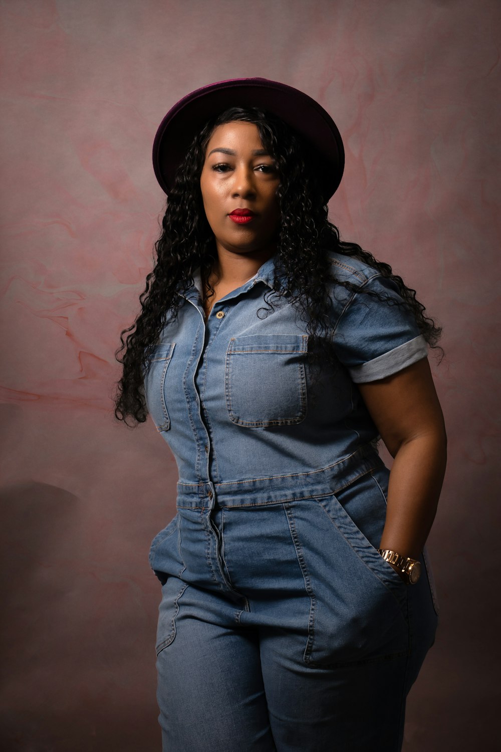 a woman in overalls and a hat poses for a picture