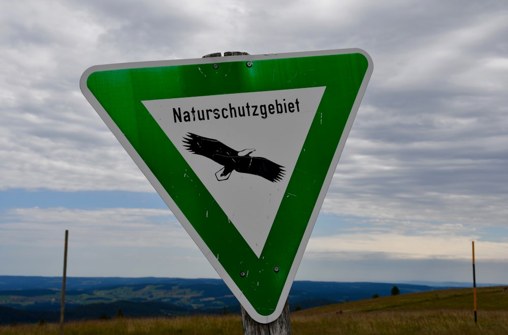 a green and white sign with a bird on it