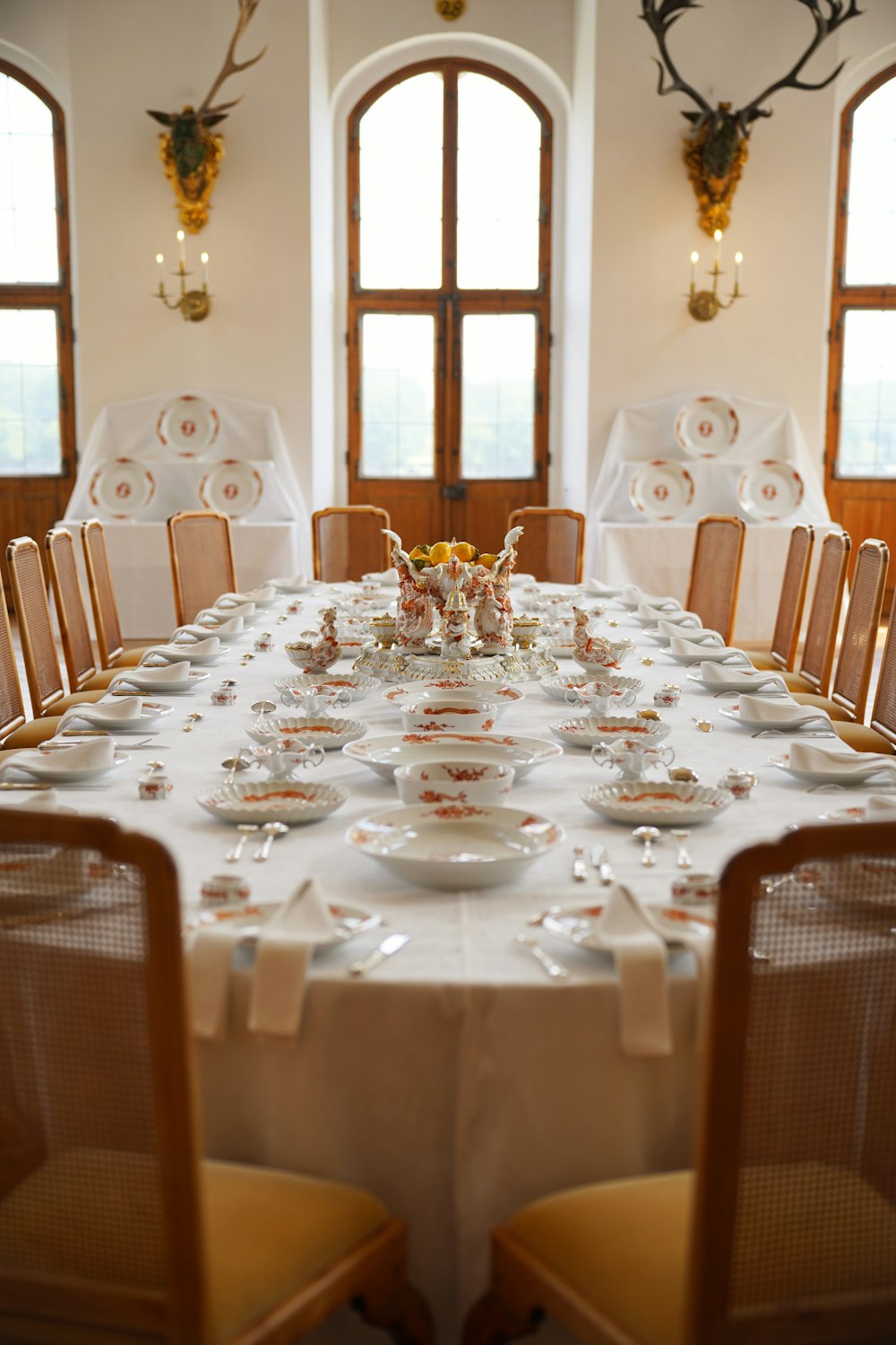 a table set for a formal dinner with deer heads on the wall