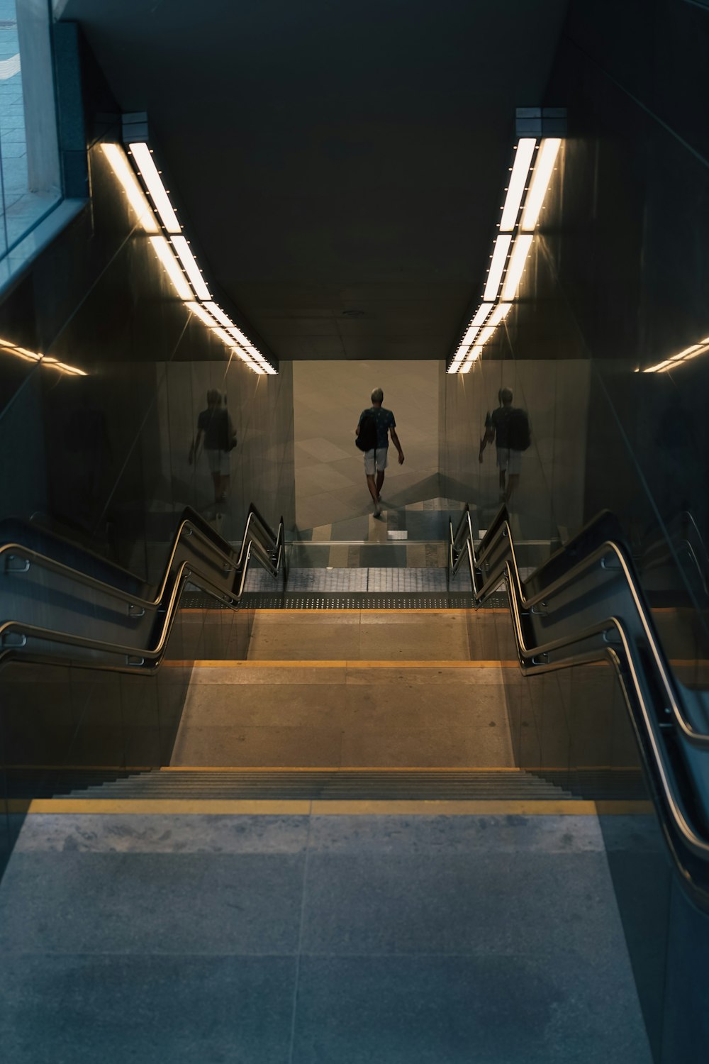 an escalator with two people walking down it
