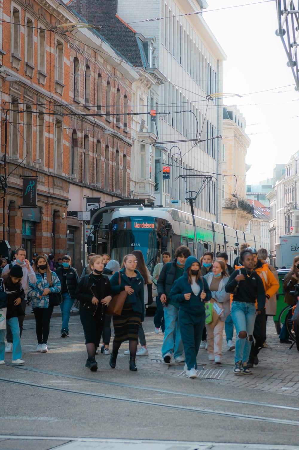 a group of people walking down a street next to a bus