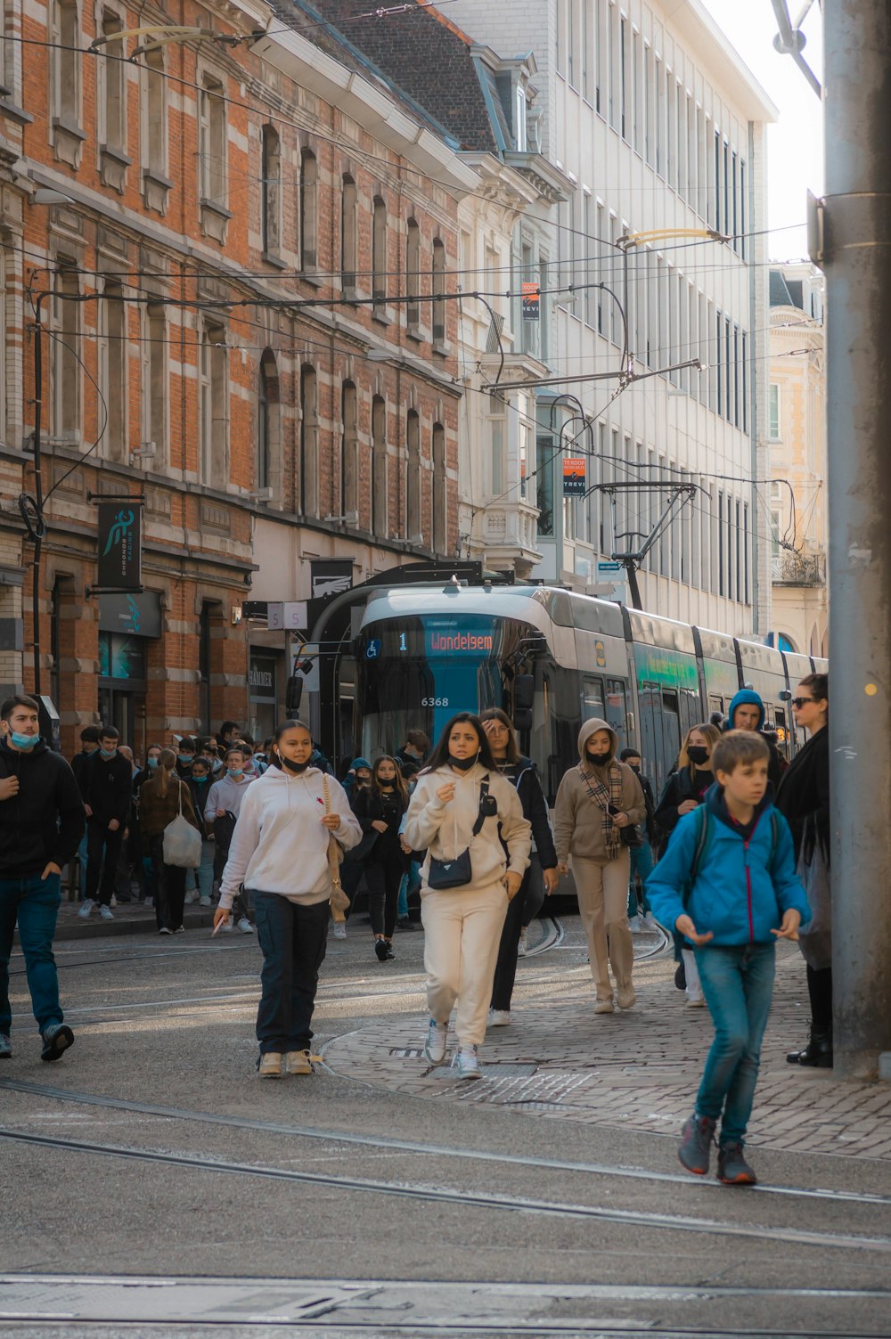 a group of people walking down a street next to a train