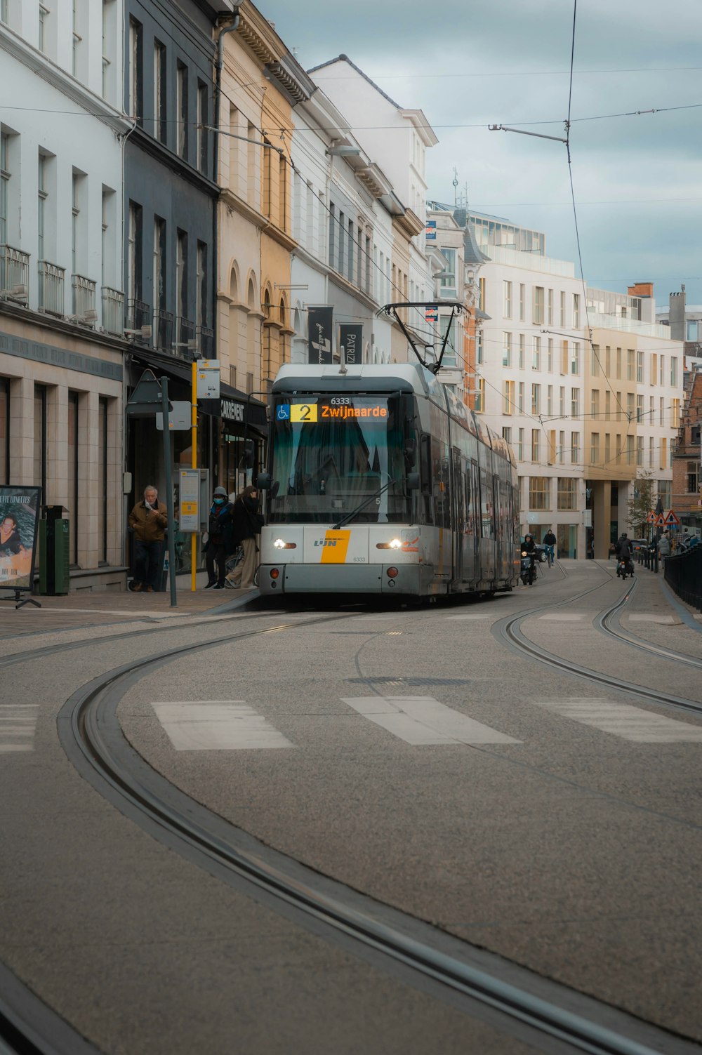 a train traveling down a street next to tall buildings