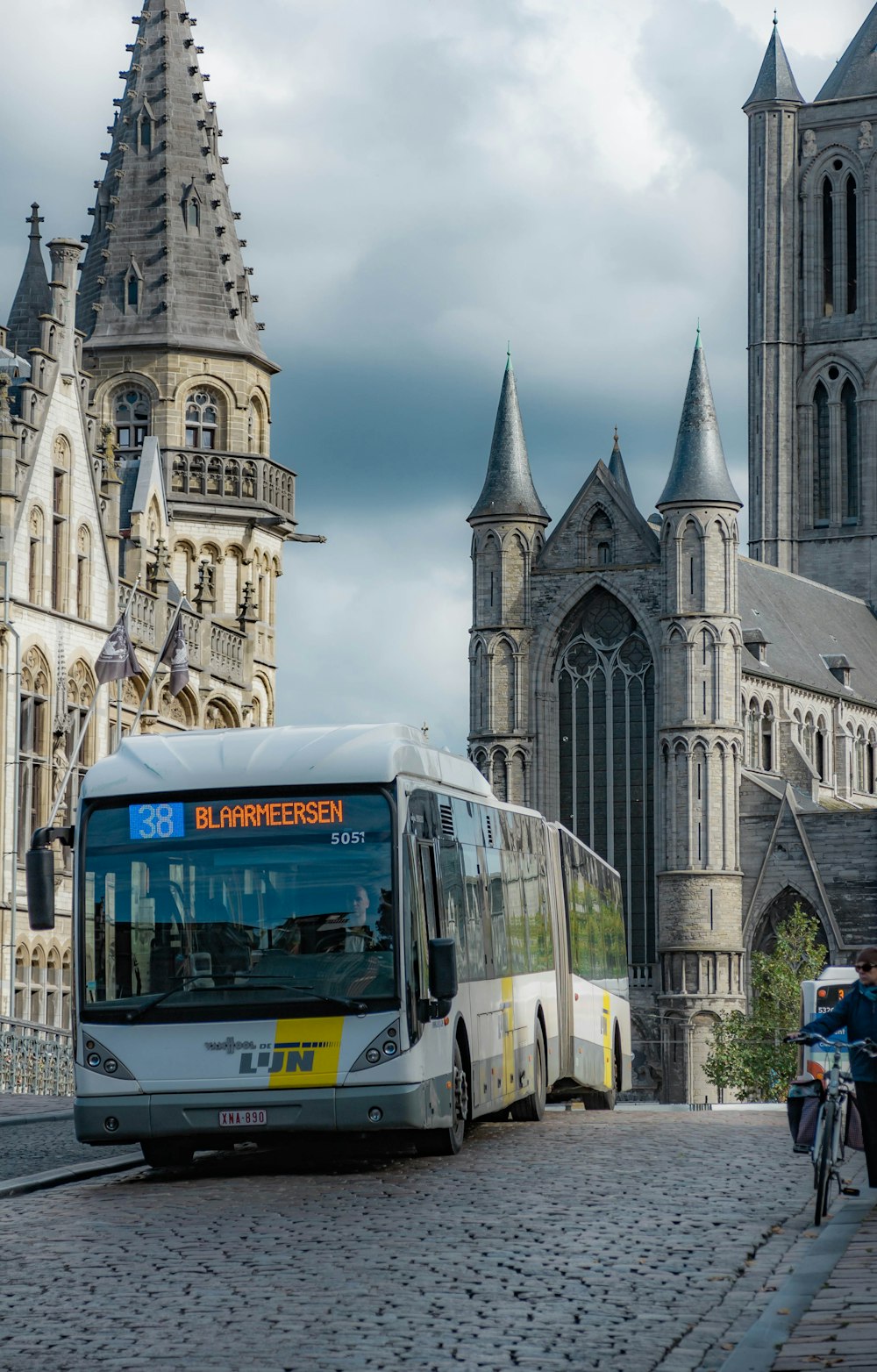 a white bus driving down a street next to tall buildings