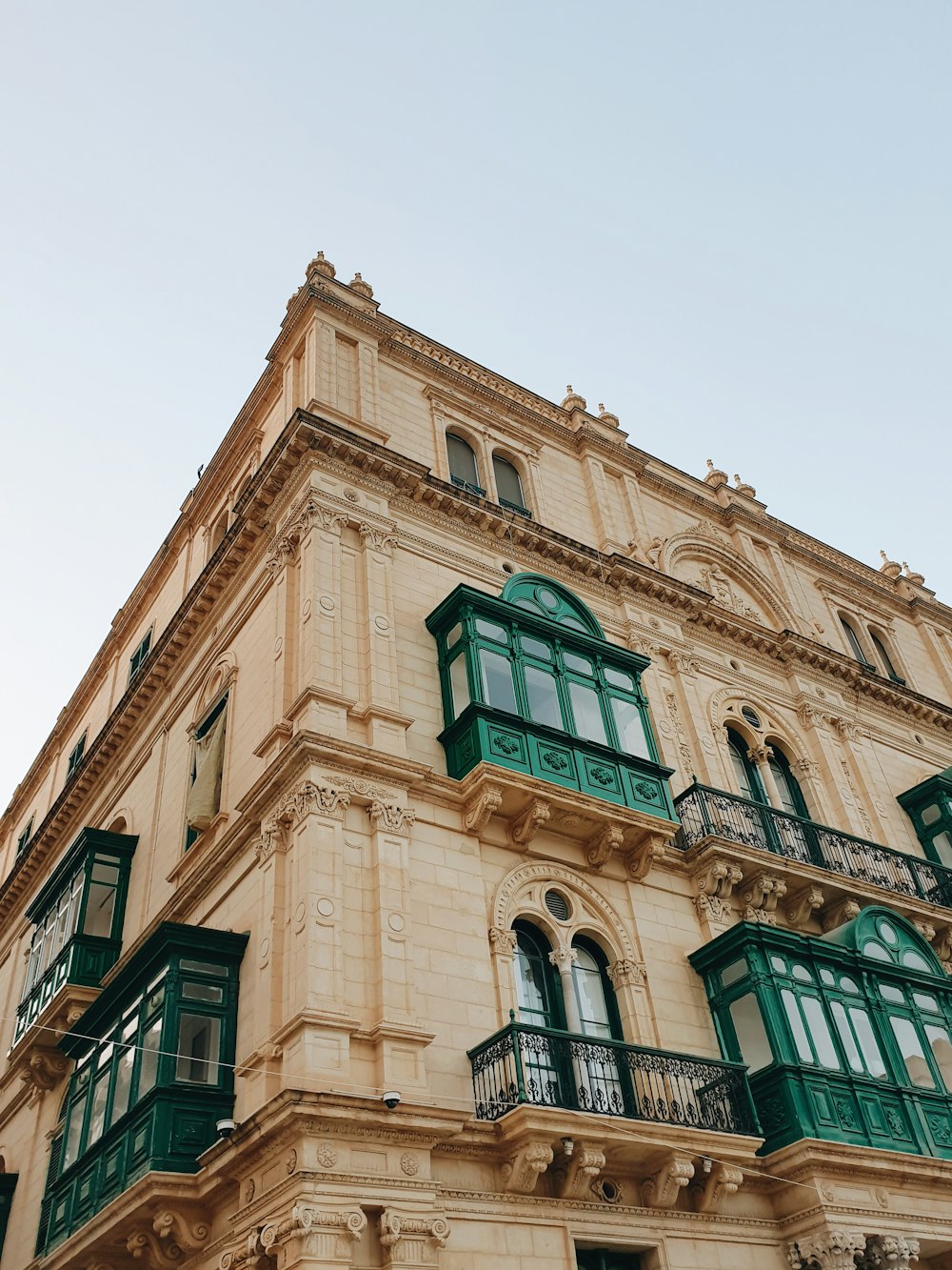 a tall building with green windows and balconies