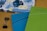 Two 2020 planners or notebooks are prominently displayed, one in blue and the other in green, each with a decorative striped pattern. A floral design is visible in the background on another item. A black binder clip is also seen on the wooden surface.