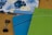 Two 2020 planners or notebooks are prominently displayed, one in blue and the other in green, each with a decorative striped pattern. A floral design is visible in the background on another item. A black binder clip is also seen on the wooden surface.