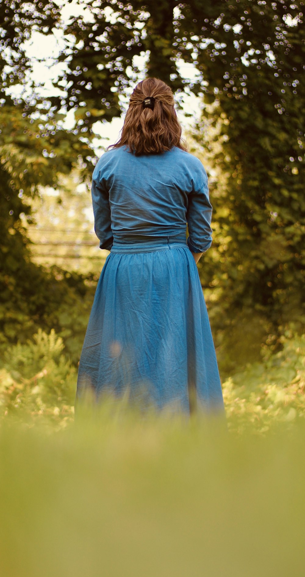 a woman in a blue dress standing in a field