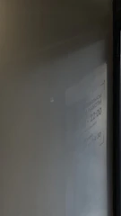 A blurred reflection of text on a wall, showing hours of operation in Cyrillic script, mostly illegible due to the lighting and angle.