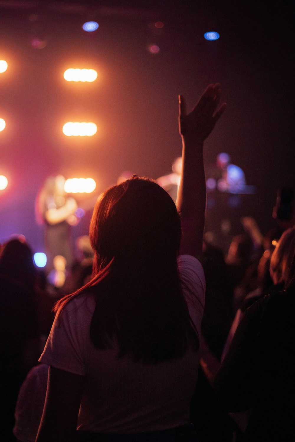 a woman raising her hand in the air at a concert