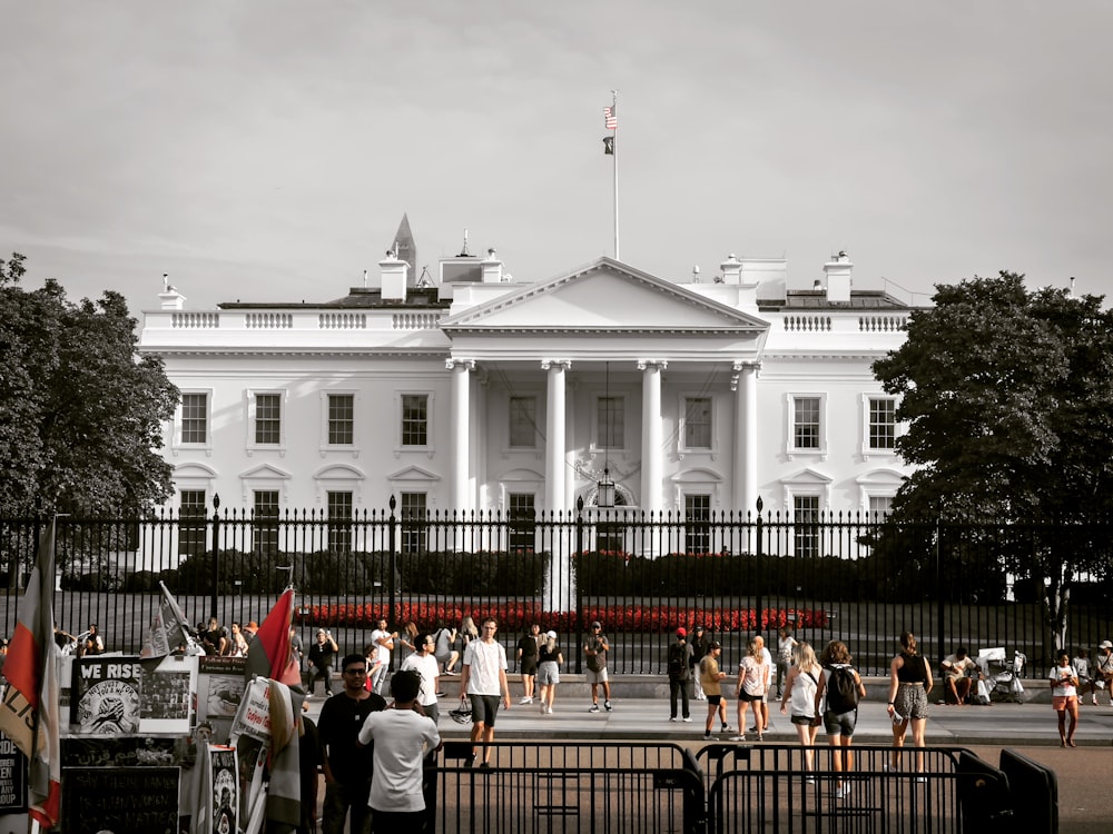 a group of people standing in front of a white building