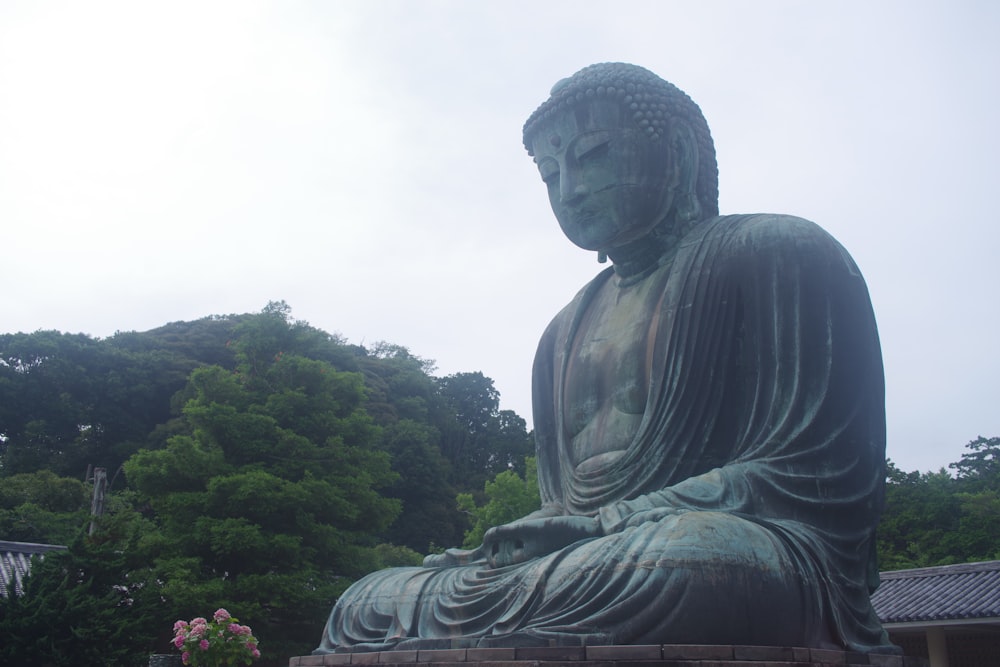 a large statue of a buddha sitting in a park
