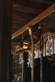 A traditional Japanese Shinto shrine featuring thick ropes, a large golden bell, and paper decorations known as shide. The structure is made of dark wood with intricate patterns, creating a serene and sacred atmosphere.