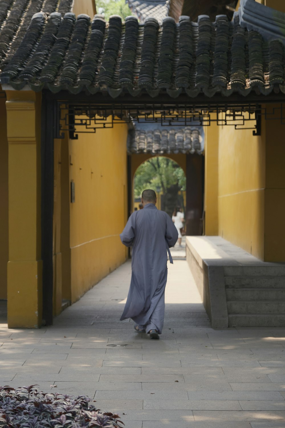 a man walking down a walkway in a courtyard