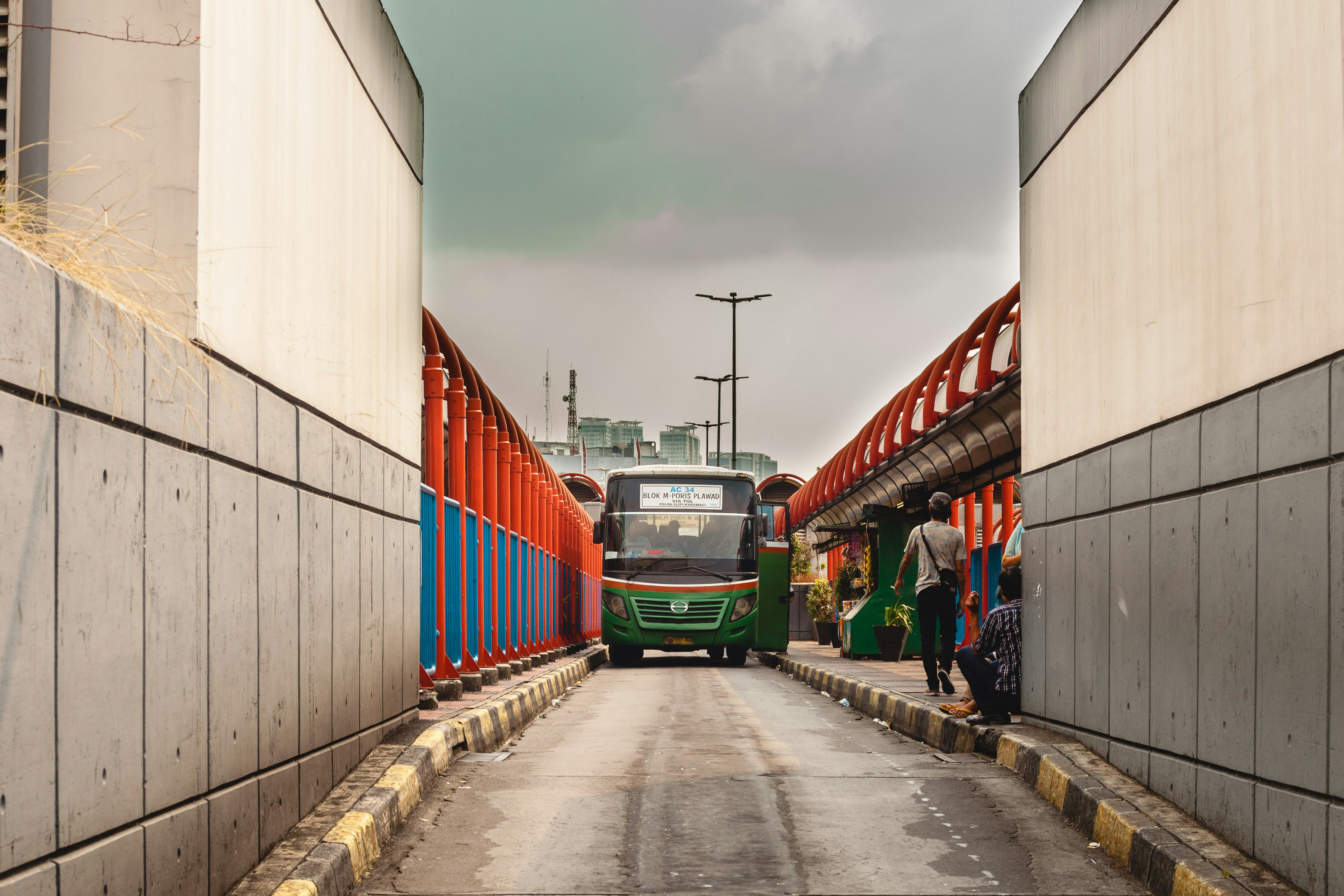 a green and red bus driving down a street