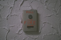 Fire detection call point mounted on a textured wall ready for emergency use.