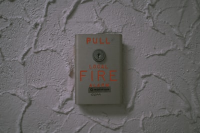 Fire detection call point mounted on a textured wall ready for emergency use.